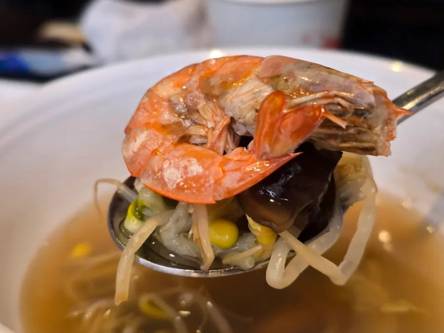 Seafood being scooped out with rich broth