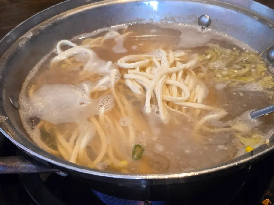 Freshly cut kalguksu noodles added into the seafood pot