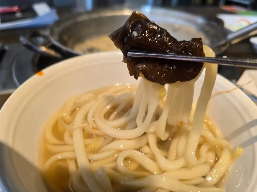 Seafood kalguksu scooped into a small bowl with broth