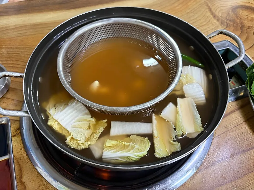 Pot of shabu-shabu broth and vegetables served at the table