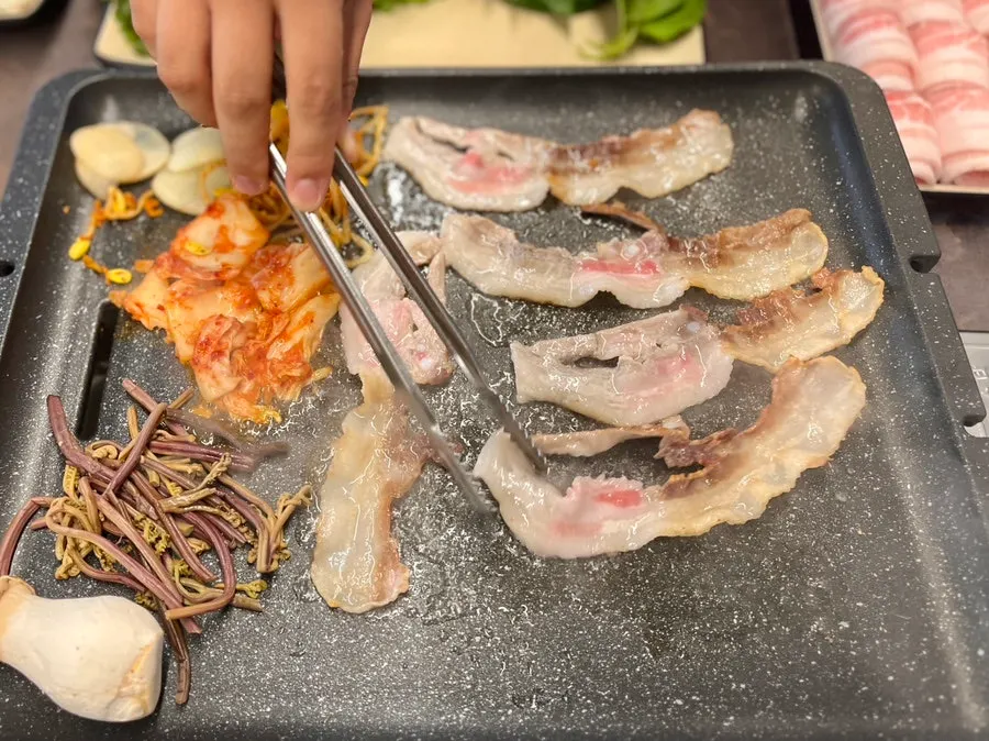 Grill topped with kimchi, bracken fern, and mushrooms