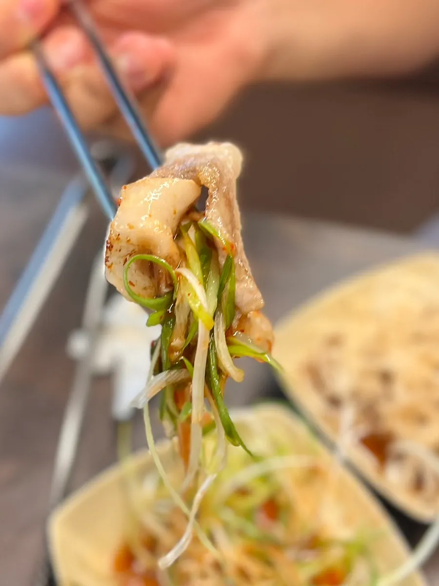 A piece of thin-cut pork belly topped with shredded green onion