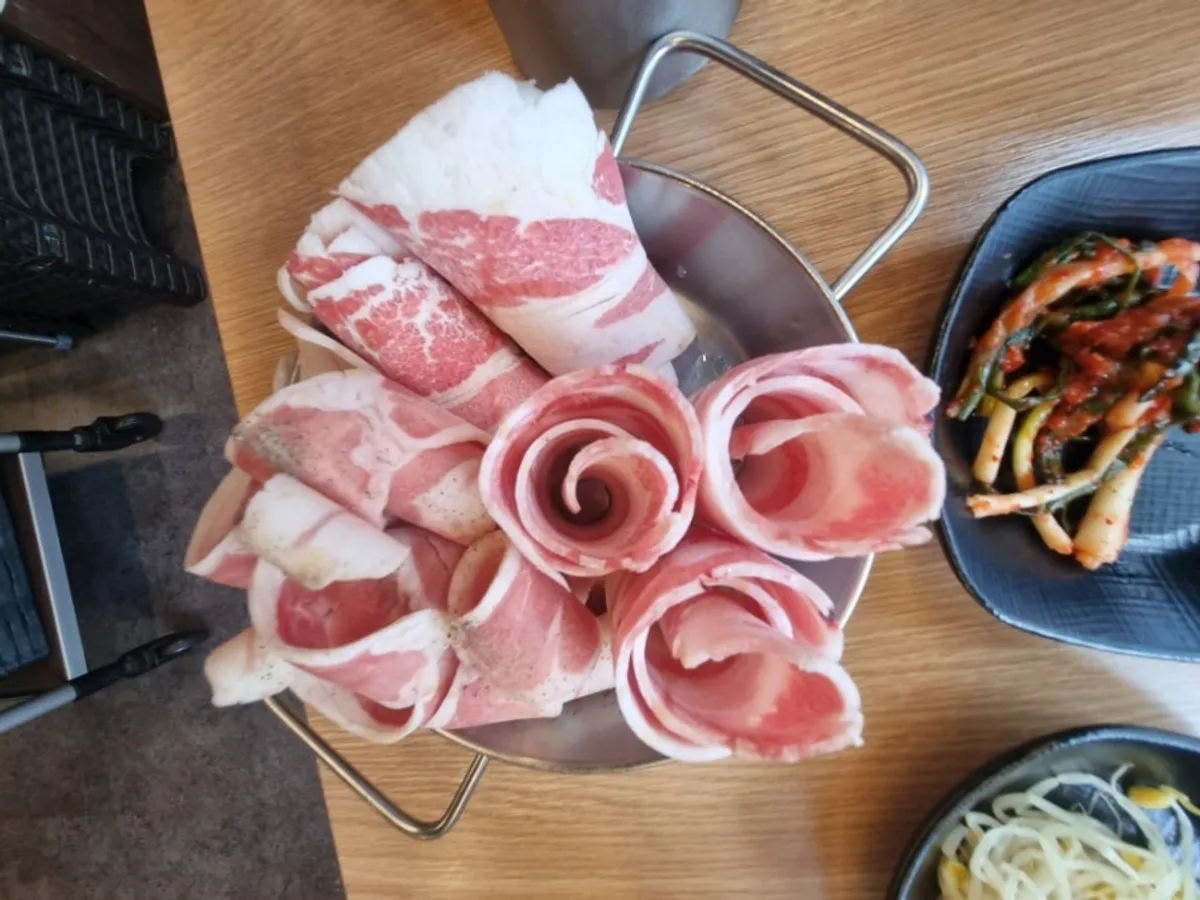 Thin-sliced pork belly cooking on the grill