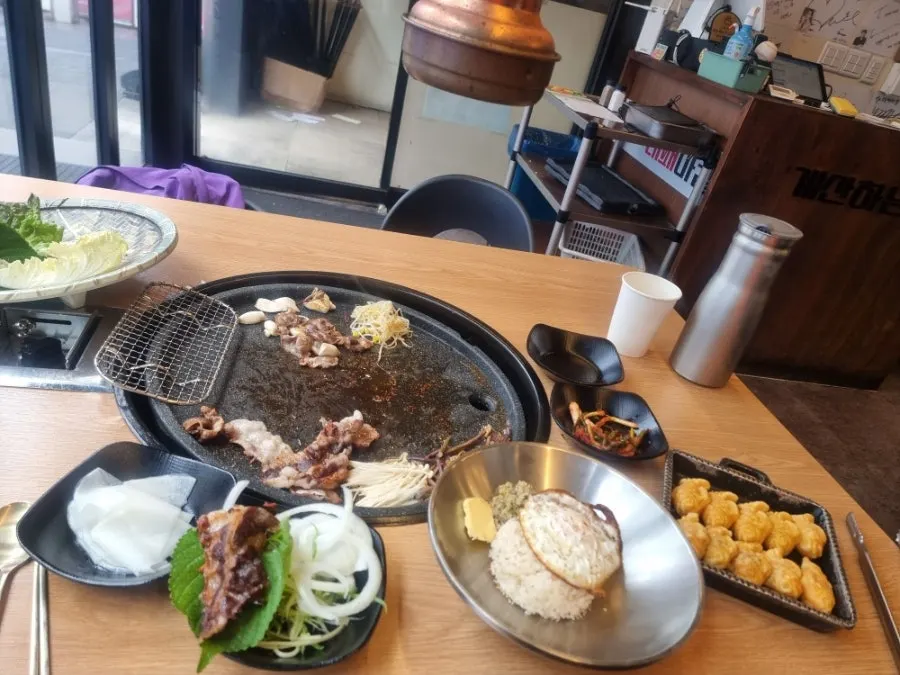 Meat and side dishes grilling together on the pan