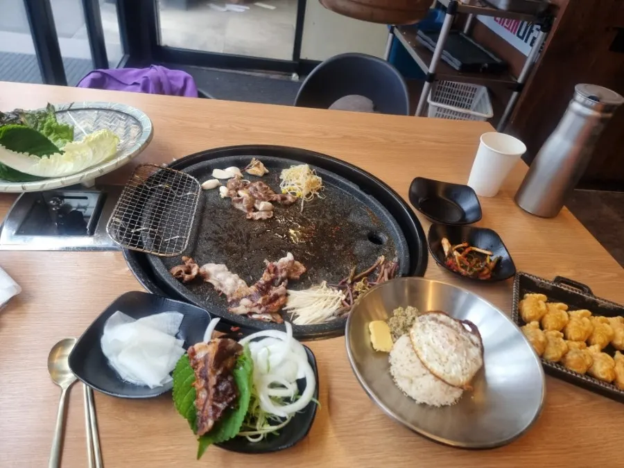 A table spread of pork belly served with soju