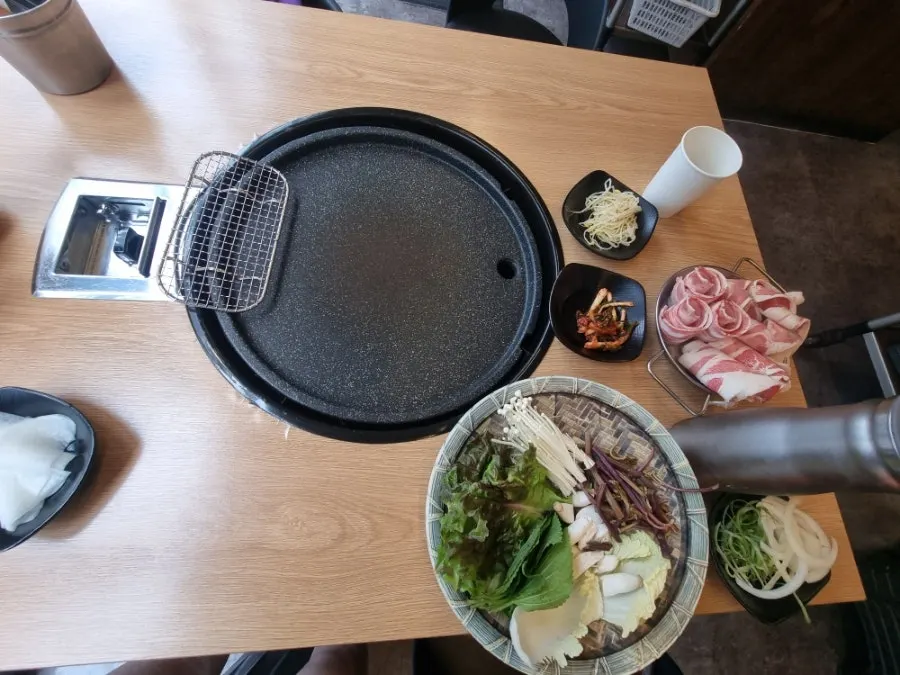 Self-serve side dishes including kimchi, seasoned bean sprouts and bracken fern
