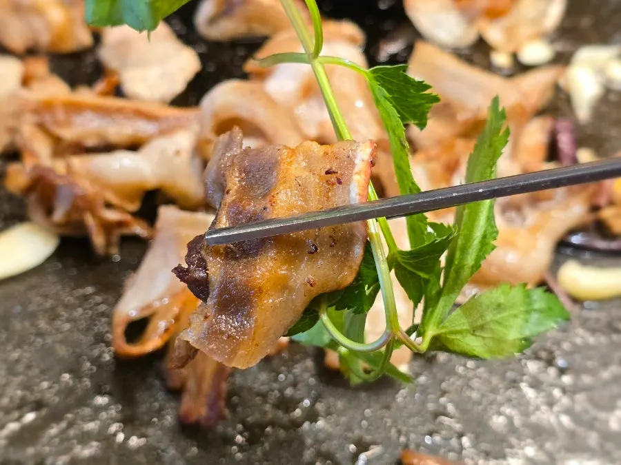 Chewy pork belly placed on perilla leaves and minari