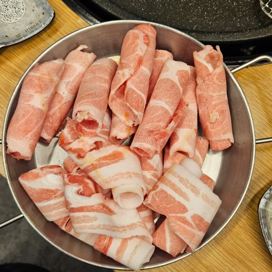 Sliced pork belly spread out on the grill