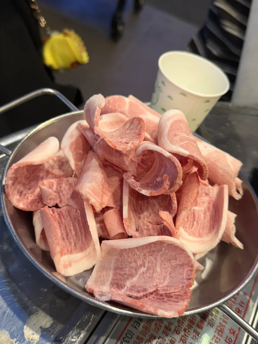A plate of thin-sliced pork belly cut into bite-sized pieces