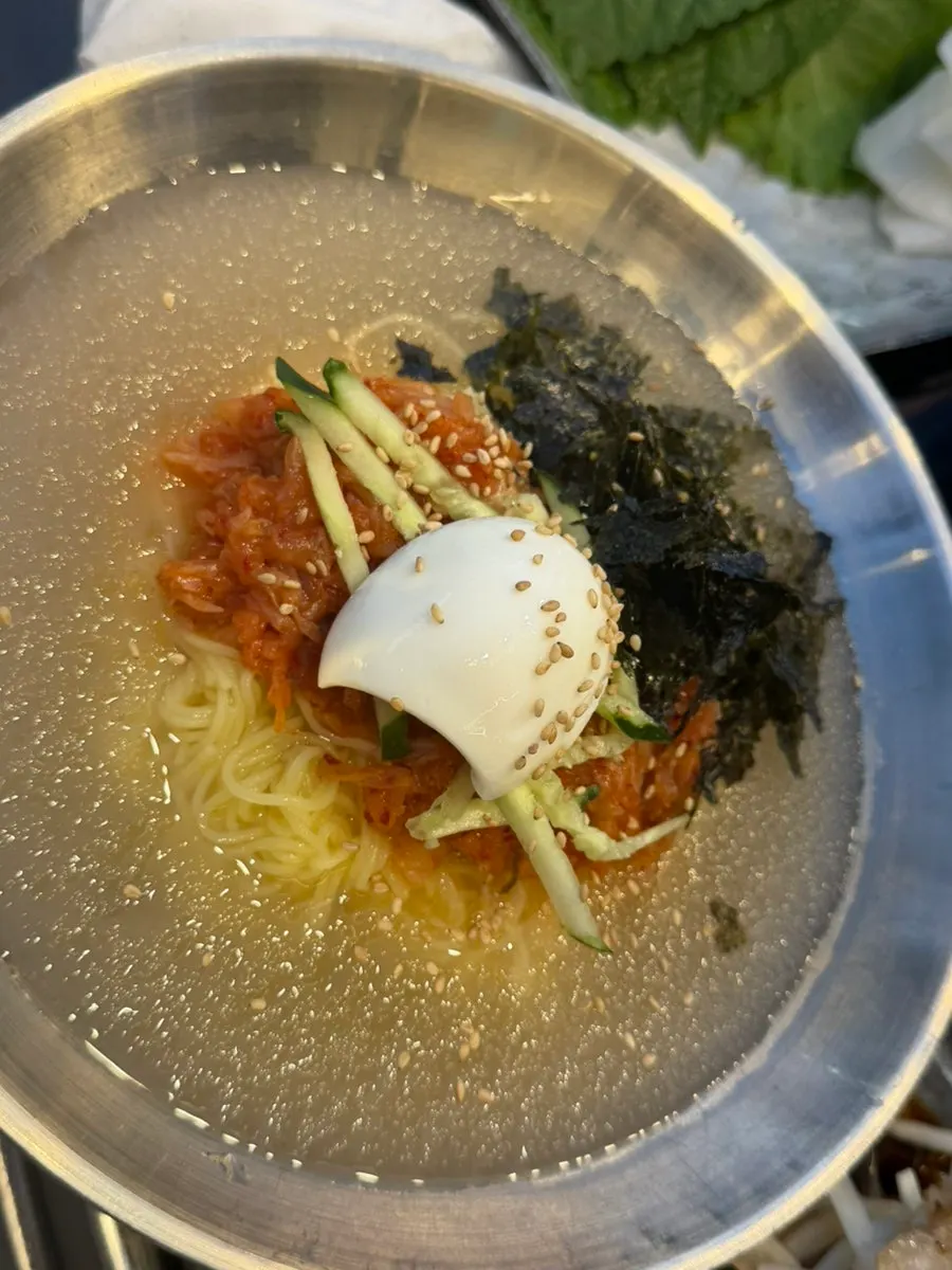 Cold kimchi noodle soup topped with slushy ice