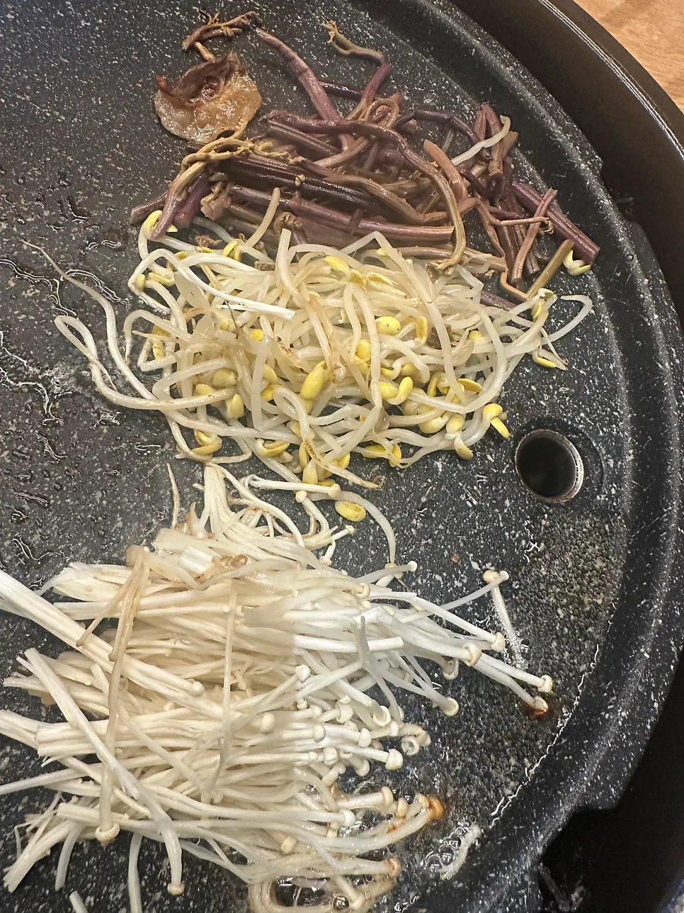 Enoki mushrooms, bean sprouts, and bracken fern grilled together on the pan