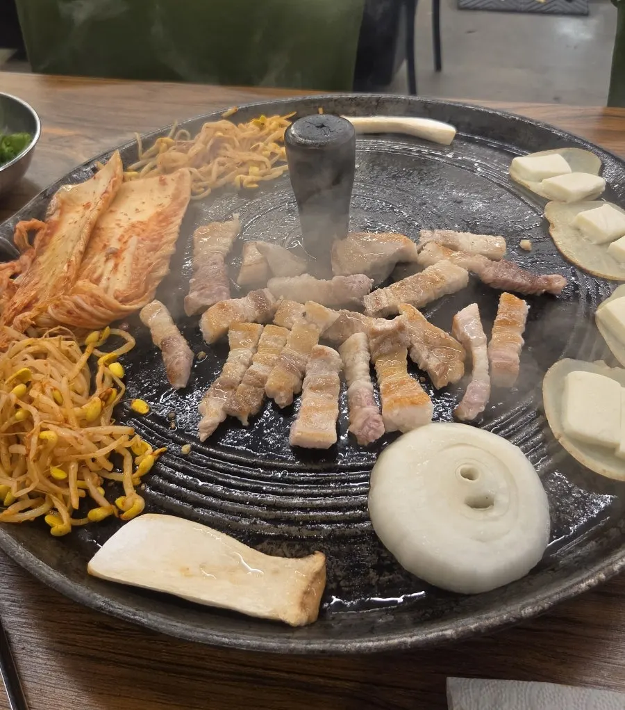 솥뚜껑 불판에 올라간 삼겹살과 목살
