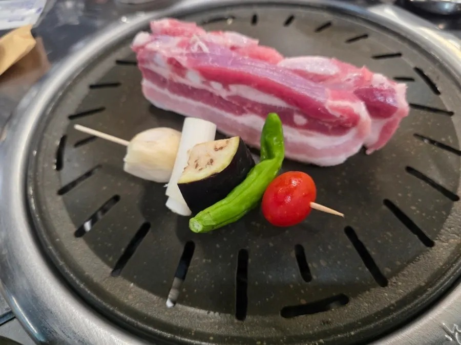 Pork belly grilling over charcoal