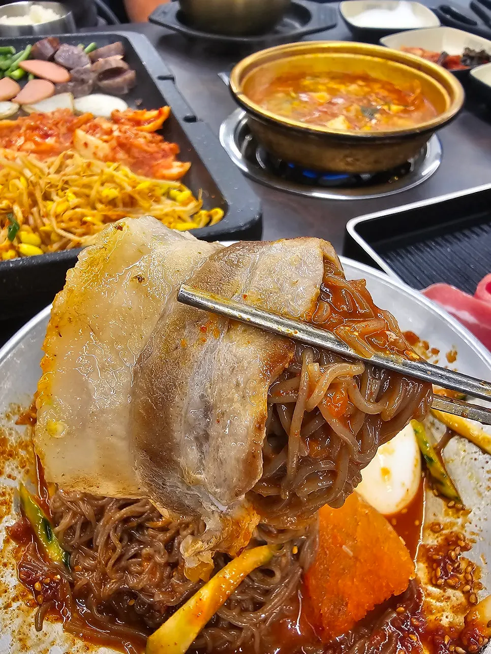 A full spread of meat, naengmyeon, and kimchi stew