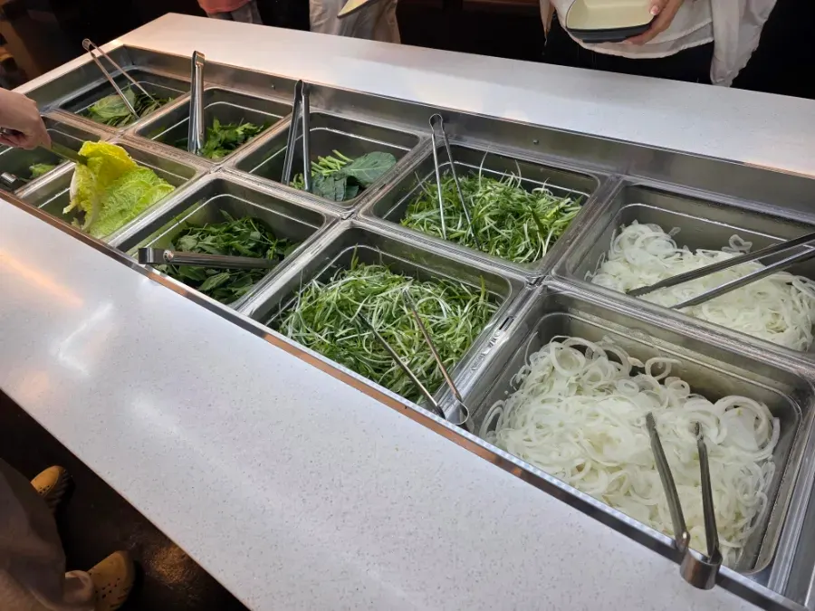 Self-serve bar section with wrap greens and vegetables