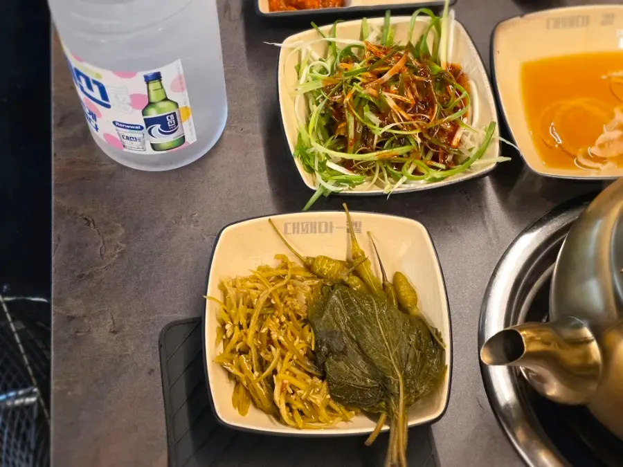 Plate of green onion salad, pepper strip pickles and other self-serve bar side dishes