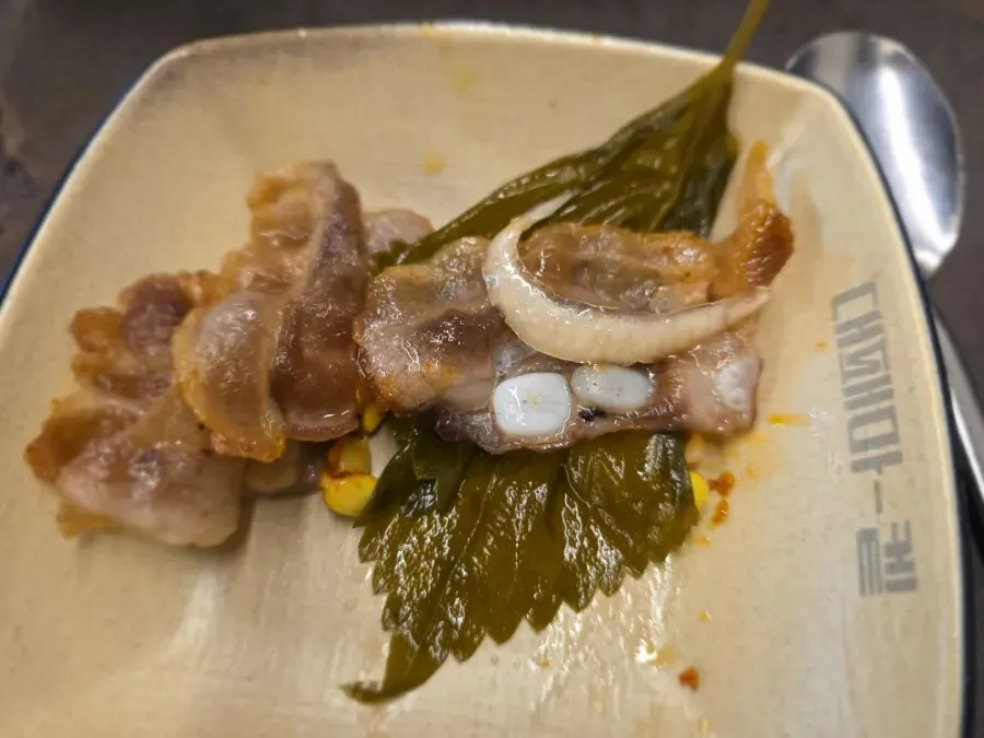 A bite of pork belly wrapped in perilla leaf pickle