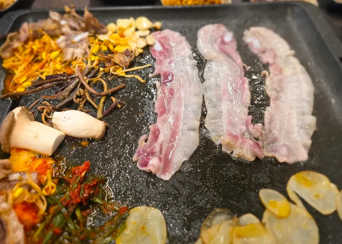Table spread with pork belly on the grill and self-serve bar side dishes