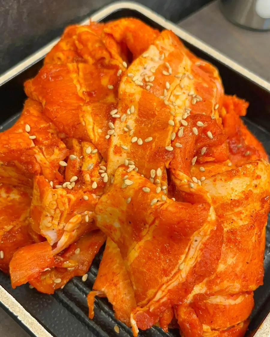 Gochujang daepae pork belly cooking on the grill
