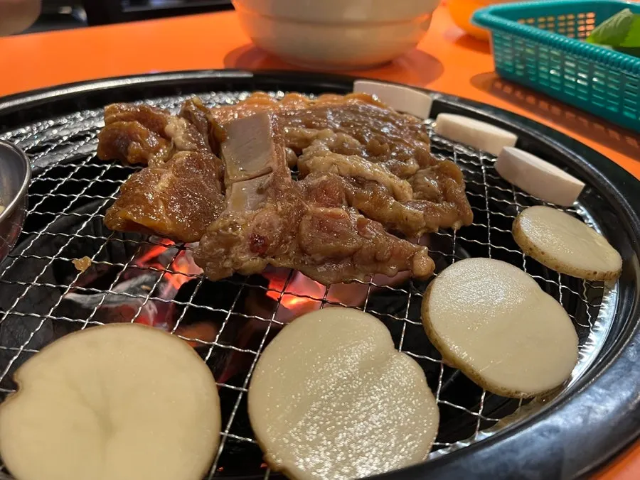 Marinated pork ribs and potatoes grilling over charcoal