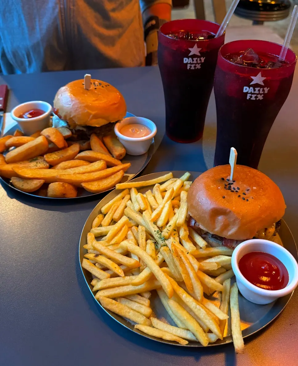 Table set with two burger sets piled high with fries