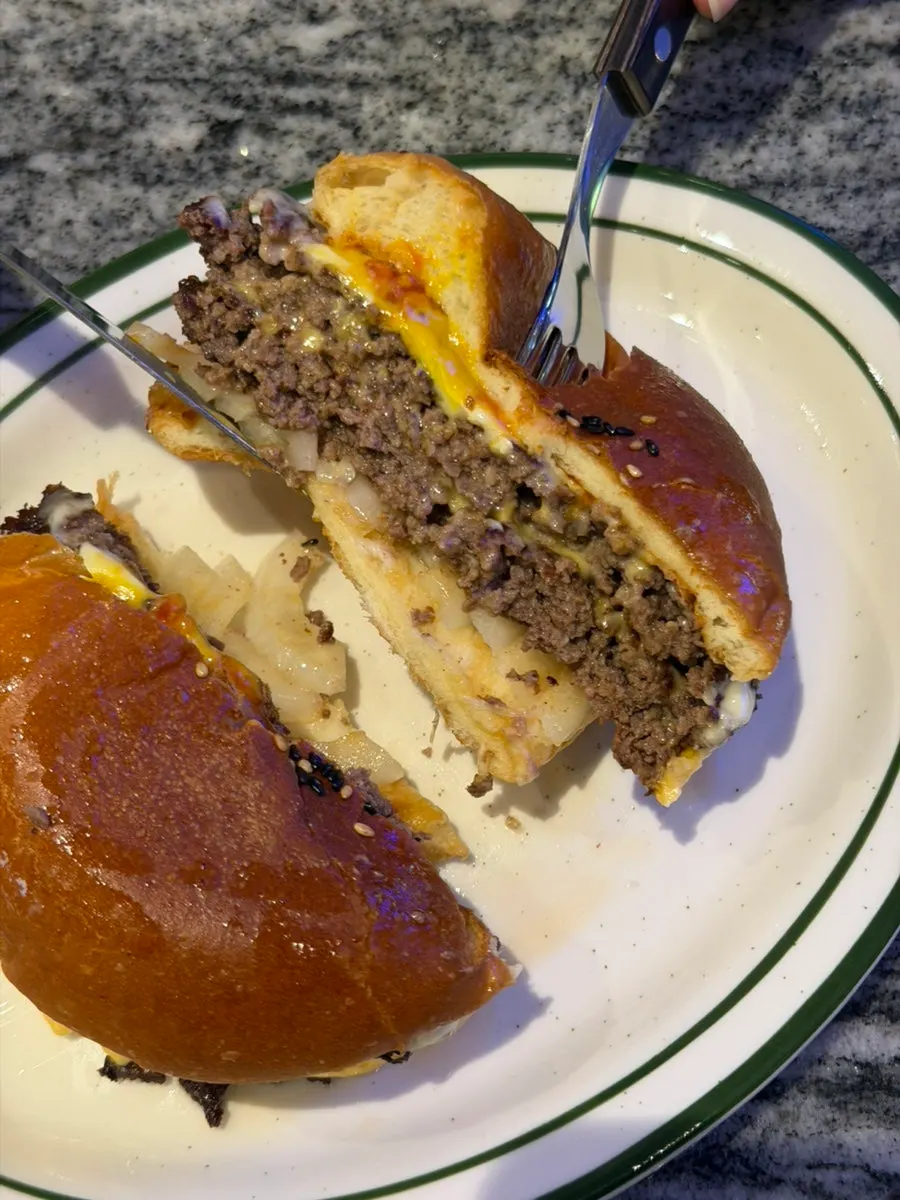 Pressing down on the sesame-studded bun of the double cheeseburger