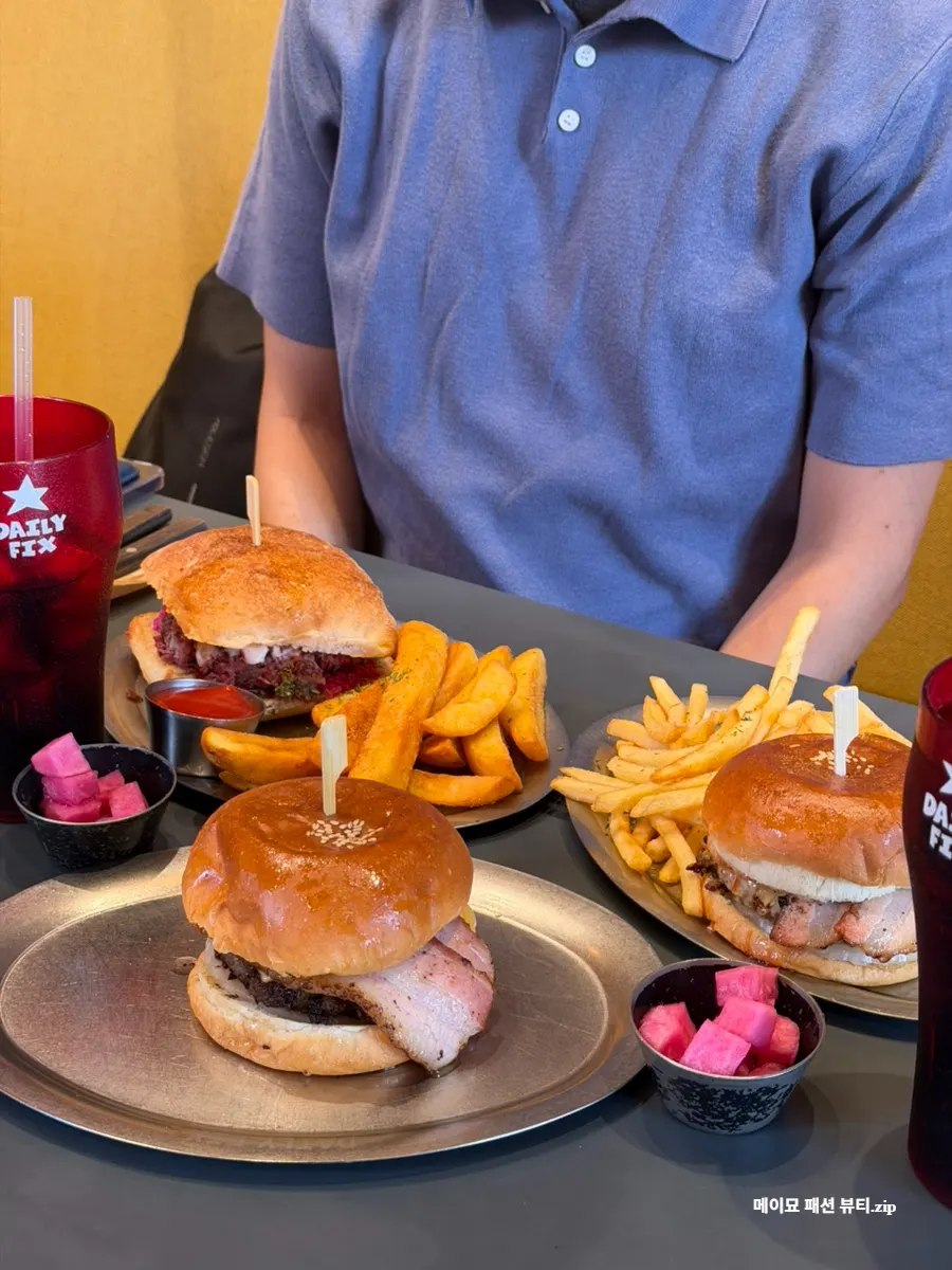 Table spread of burgers and sandwiches ordered by three people
