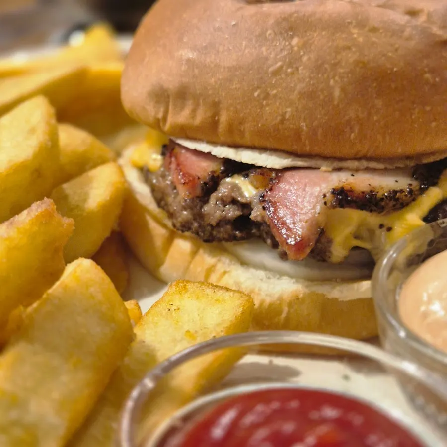 Glossy bun and thick patty of the bacon cheeseburger