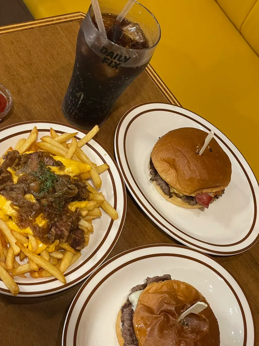 Table shot with burgers, fries and cola all together