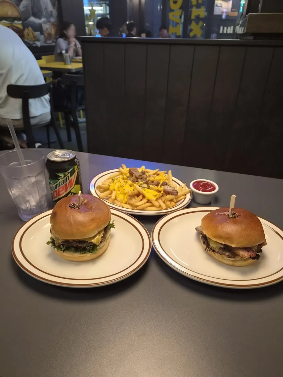 테이블에 차려진 베이컨 치즈 버거와 클래식 버거 한 상