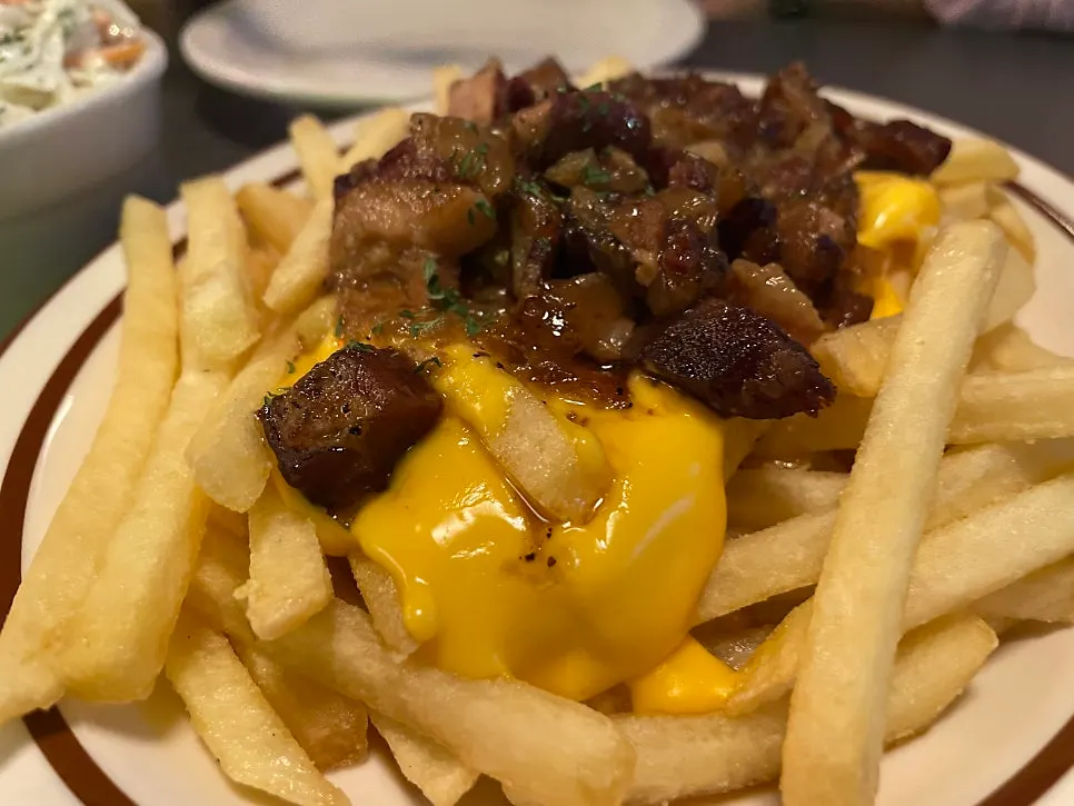 Fries topped with sautéed onions and thick bacon