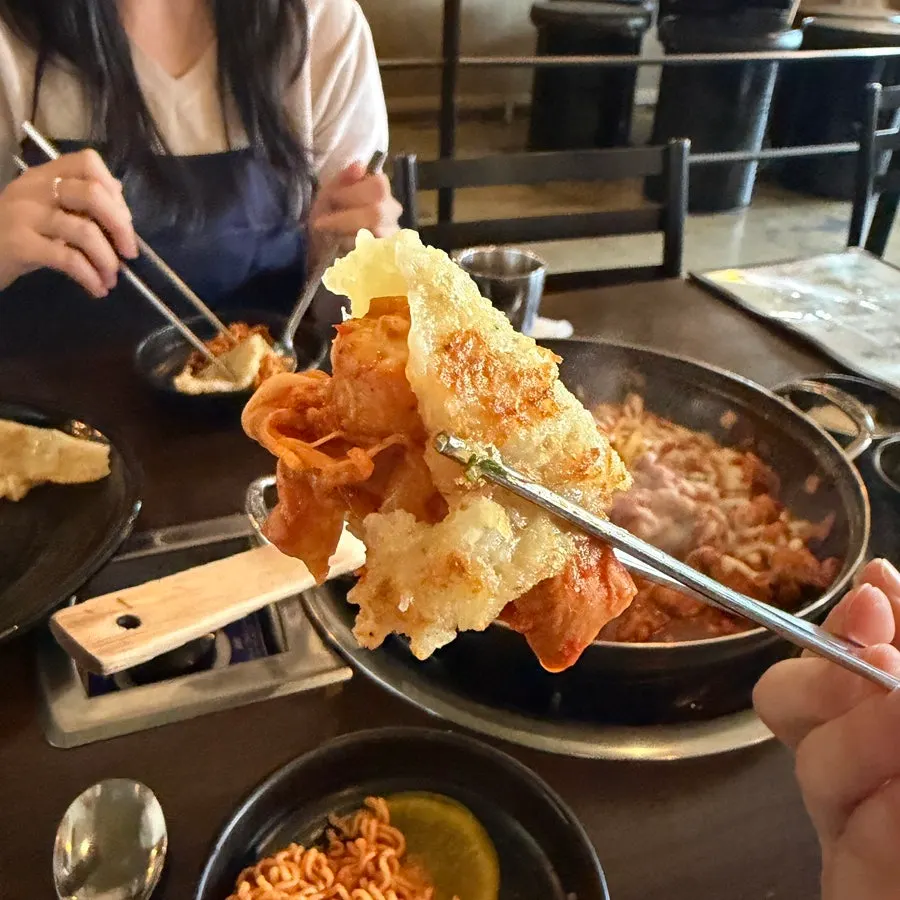 A wrap of potato pancake loaded with dakgalbi, vegetables, and cheese