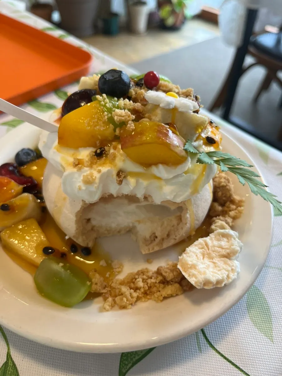 Pavlova topped with peach, shine muscat grapes, and blueberries