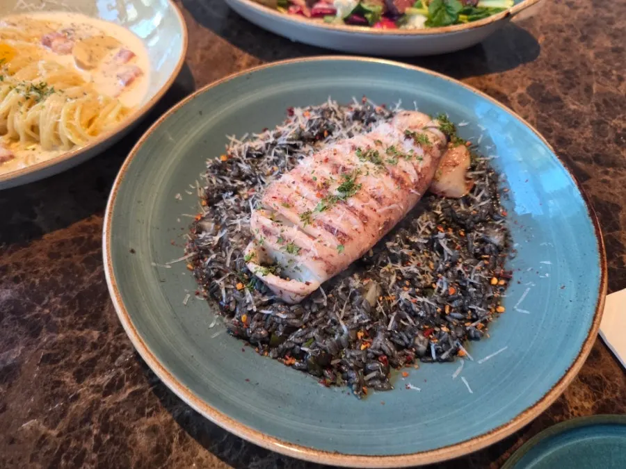 Squid ink risotto topped with a whole squid