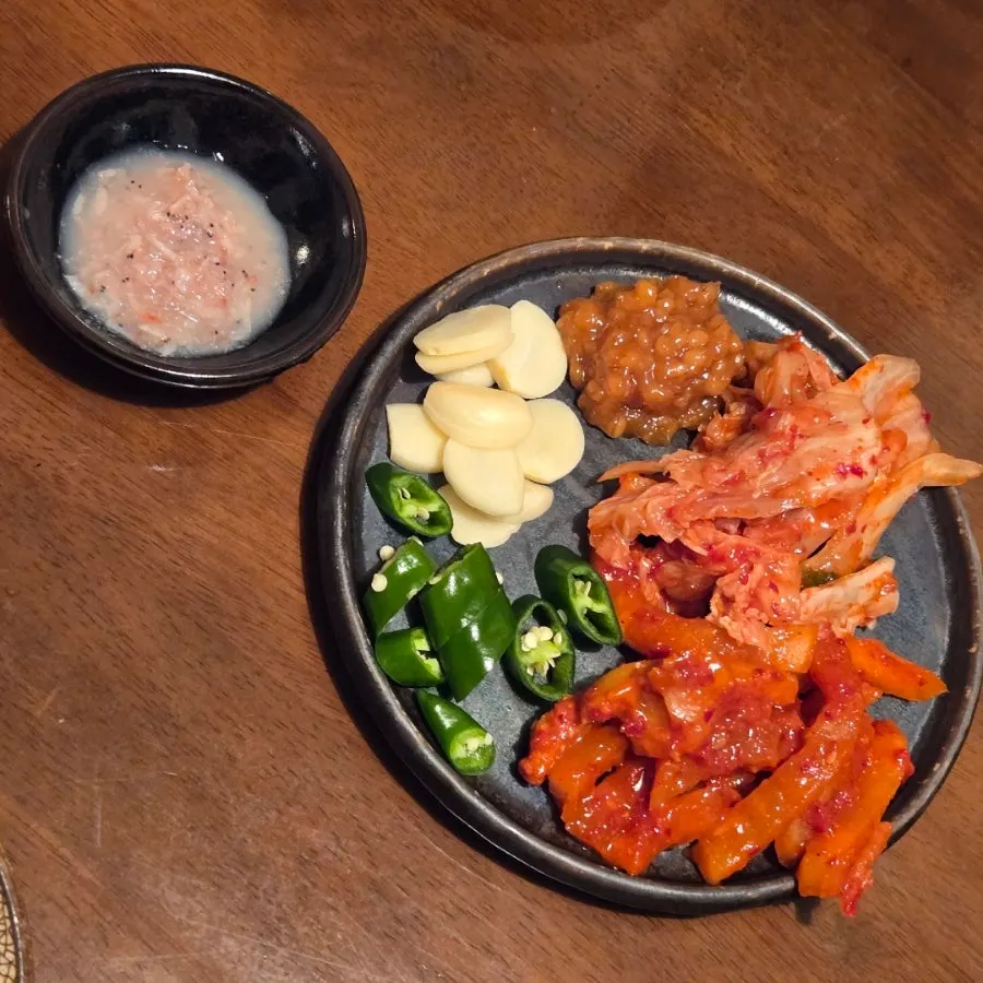 Side dishes and wrap greens at Dambaek Jujeom including cabbage kimchi and dried radish
