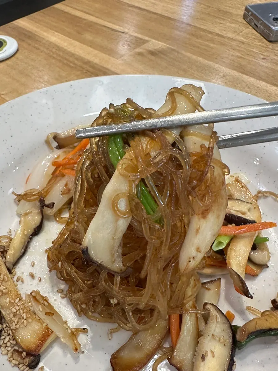 Close-up of japchae with mushrooms, carrots, and onions