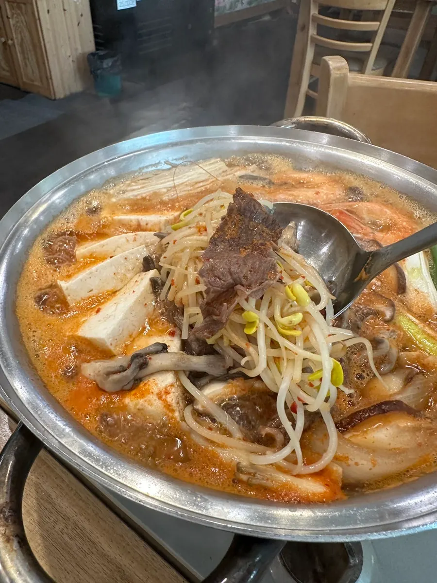 Hot pot broth filled with tofu, mushrooms, and bean sprouts
