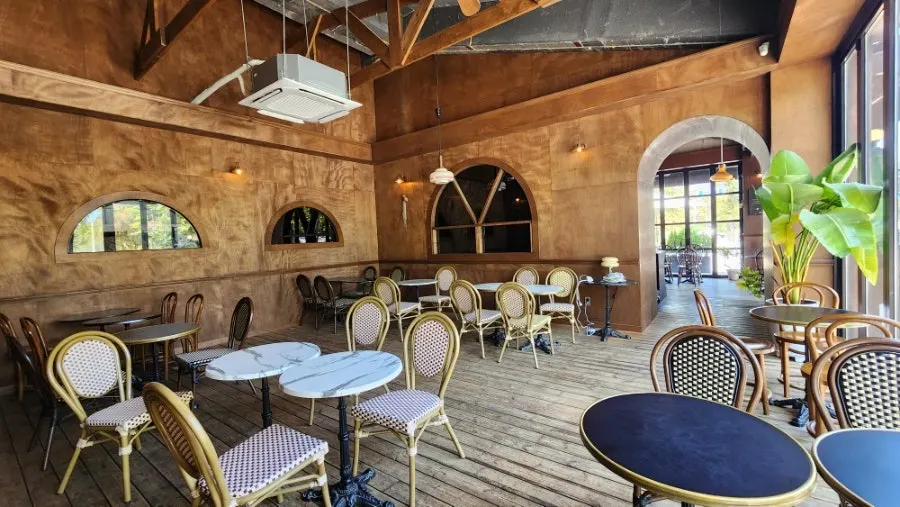 Interior Frank Coffin Bar dengan jendela kaca besar dan tanaman