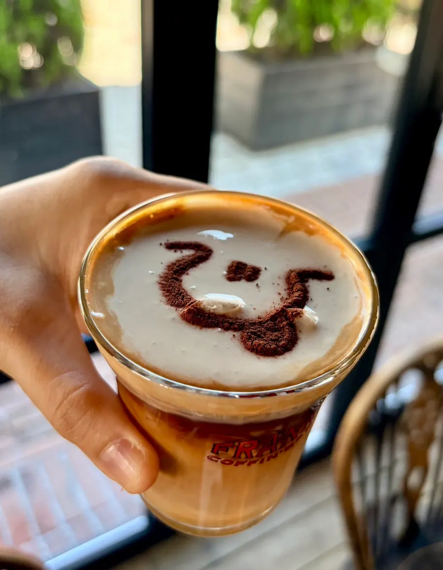 Signature Frank Coffee latte topped with cream and cinnamon powder