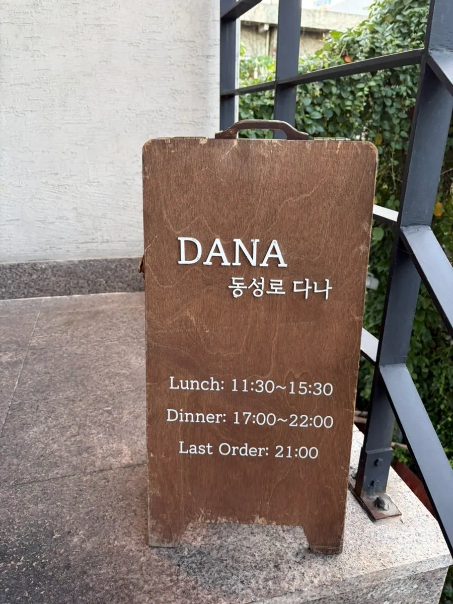 입구 앞에 놓인 메뉴판과 영업시간 안내
