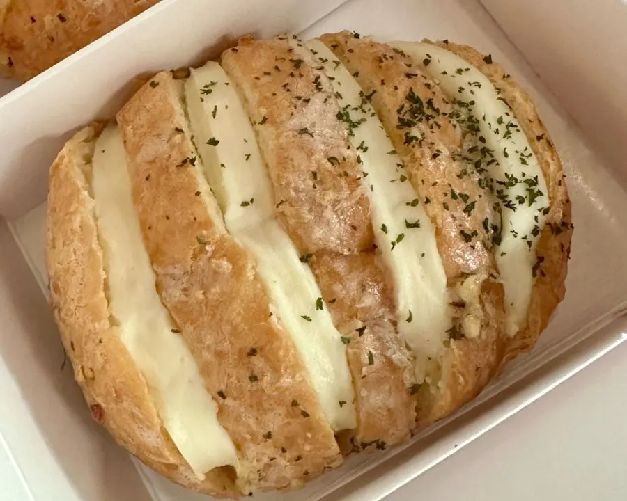 Garlic bread with cream and toppings visible through the score marks