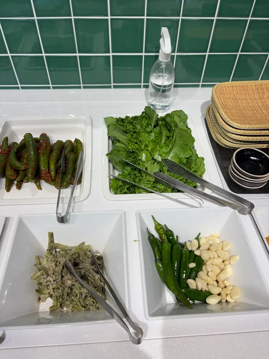 Self-serve bar with namul side dishes and ssam greens