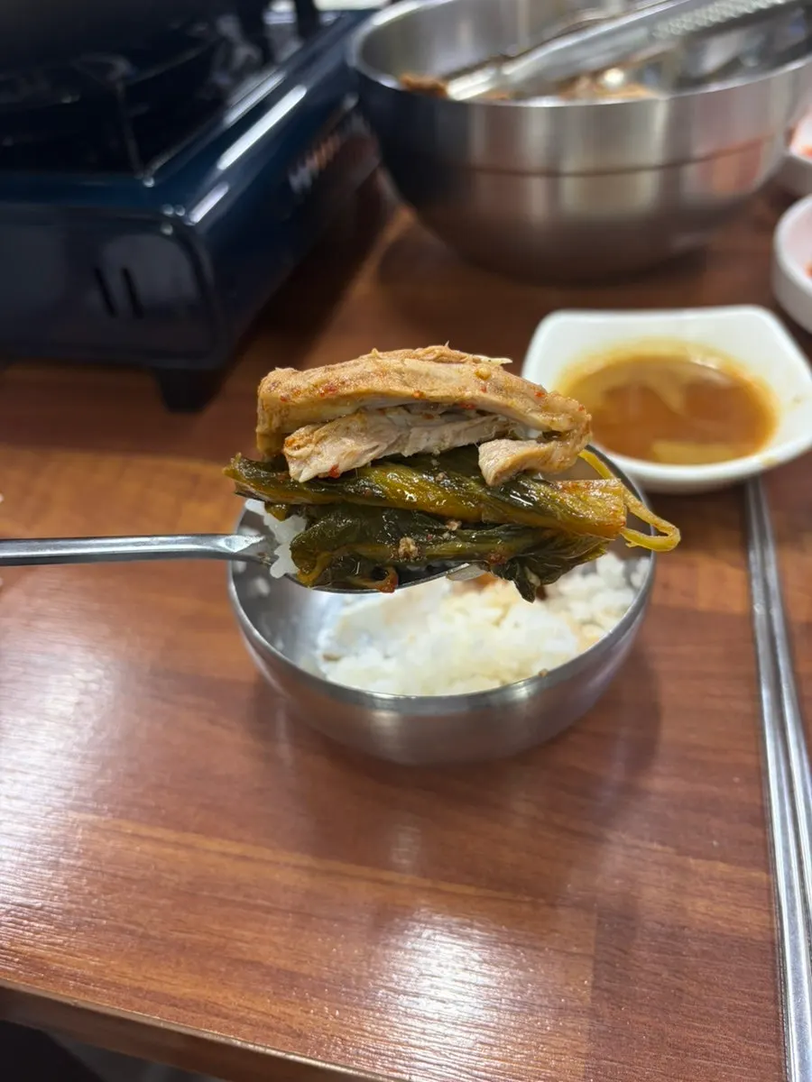 A spoonful of rice topped with meat and napa cabbage