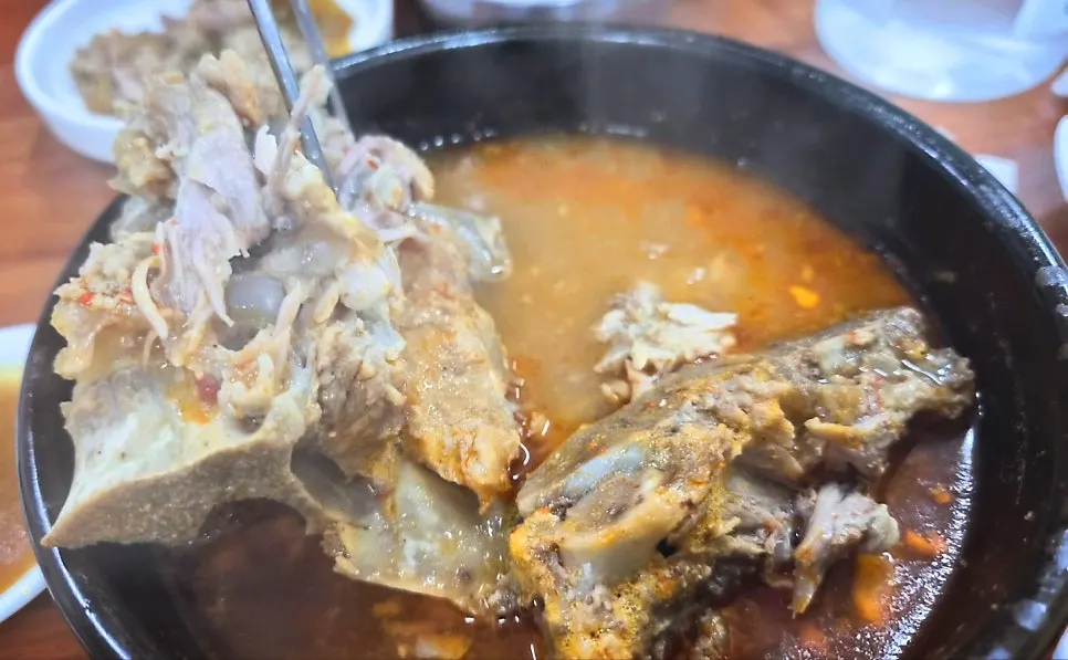 Stone bowl of hangover soup piled with ugeoji and bone-in meat