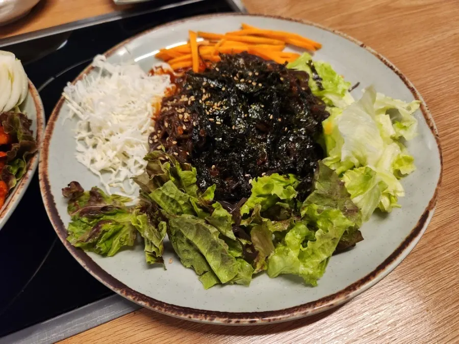 A single wrap of bossam and kimchi on a perilla leaf