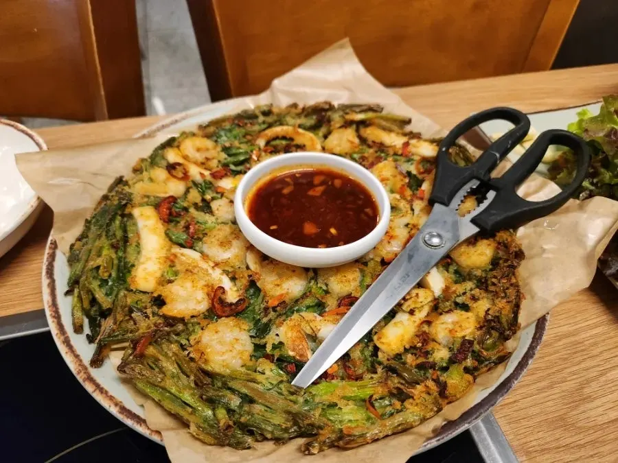 Tray makguksu topped with vegetable garnish and sauce