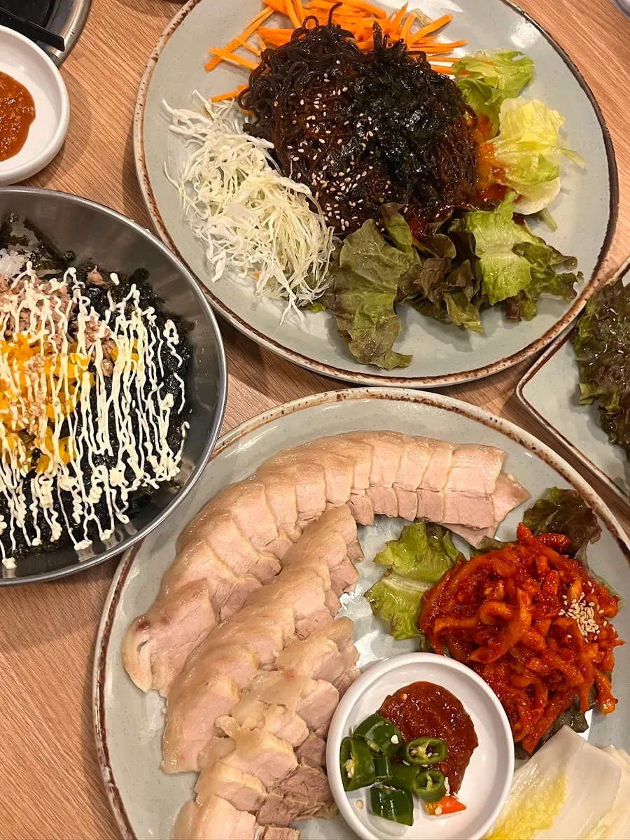 Table spread of small five-layer bossam, makguksu, and rice ball