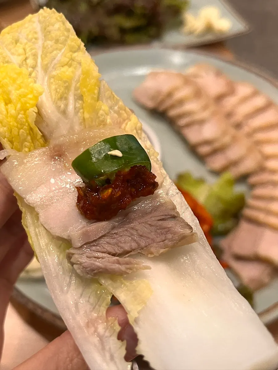A wrap of bossam meat piled on wrap cabbage