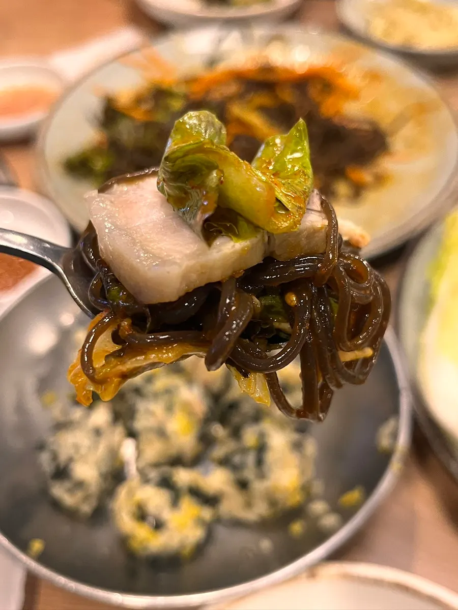 A bite of makguksu with rice ball