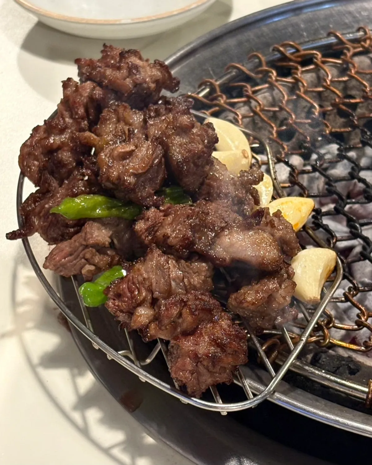Staff grilling salted galbisal over charcoal